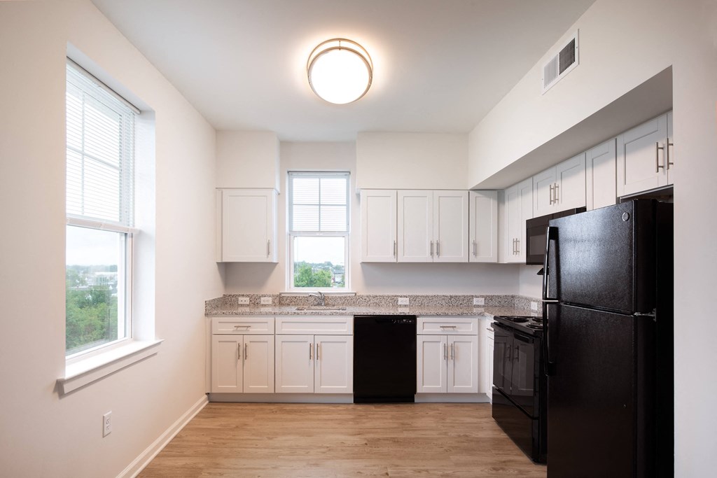 a kitchen with white cabinets and a black refrigerator