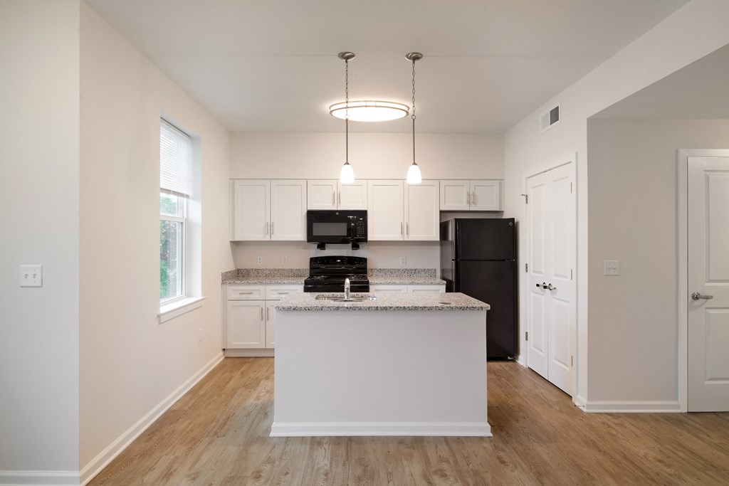 a kitchen with white cabinets and a white island with a black refrigerator