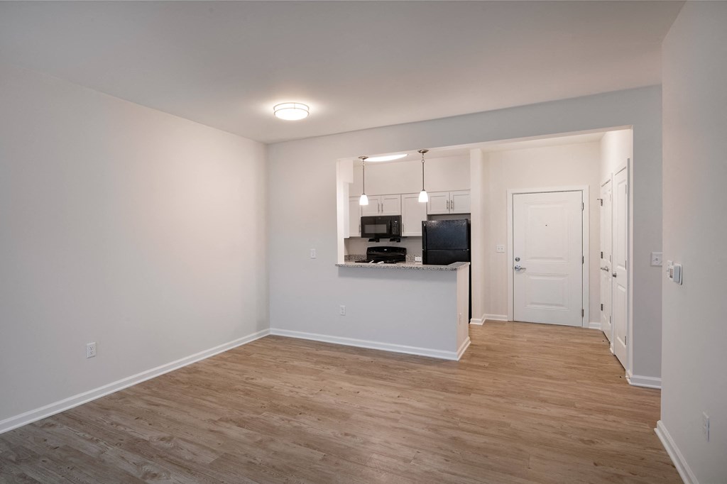 a living room and kitchen with a wood floor and white walls