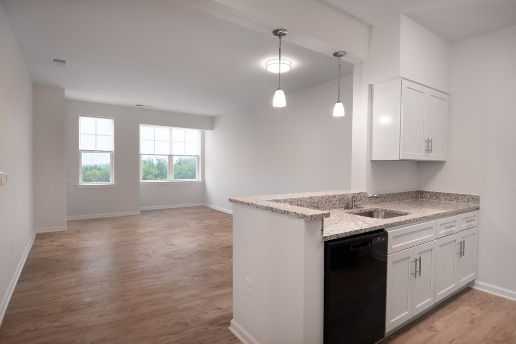an empty kitchen and living room with white cabinets and granite counter tops