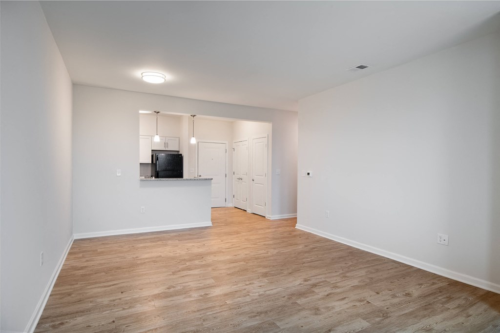 an empty living room with white walls and wood flooring