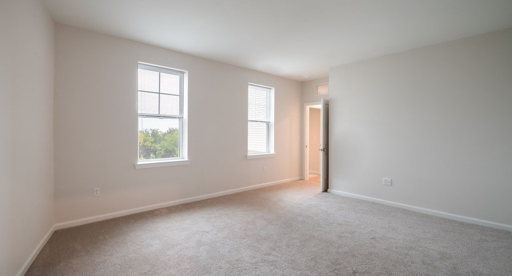 an empty living room with two windows and a door