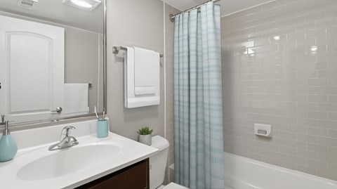 A white bathroom with a blue vase on the sink.