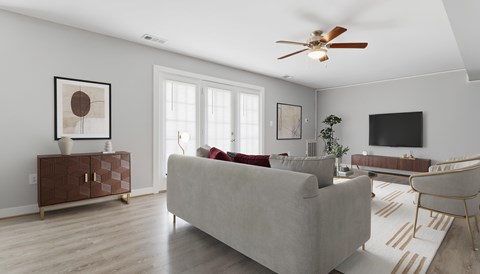 A living room with a grey couch, a brown side table, and a ceiling fan.