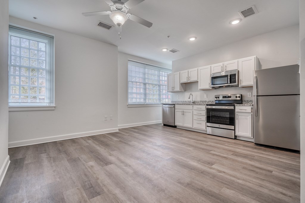 an empty kitchen with white cabinets and stainless steel appliances