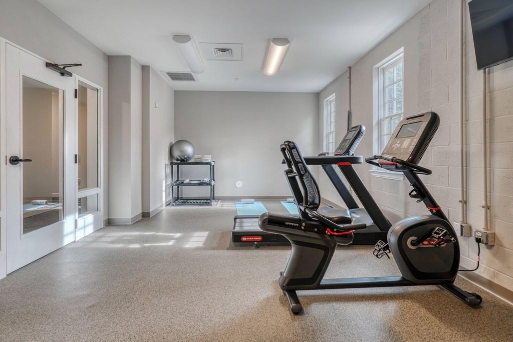 two treadmills in a gym with a door to a shower and a window