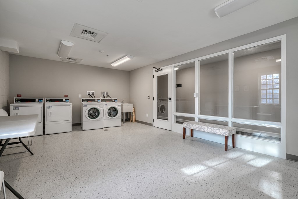 a laundry room with washes and dryers and a table with a bench