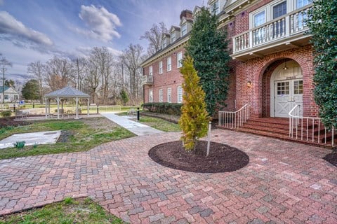 the front yard of a brick house with a gazebo and a pathway
