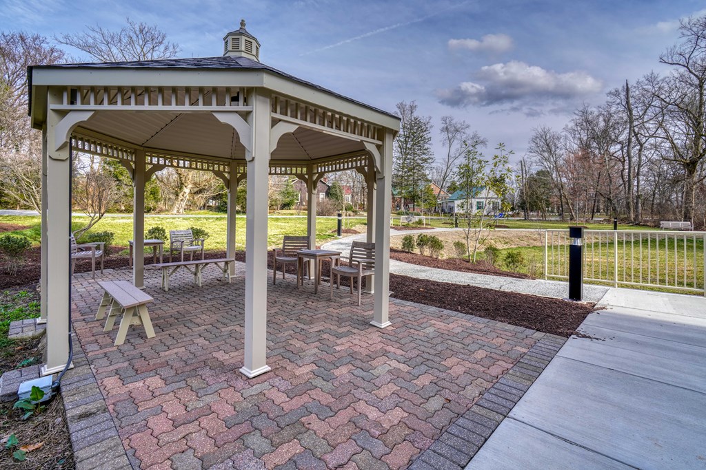 a gazebo with tables and chairs in a park