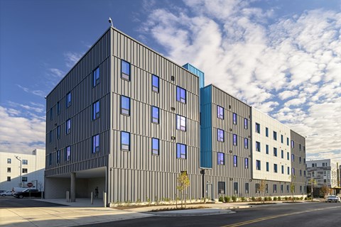 A modern building with a grey facade and blue accent windows.