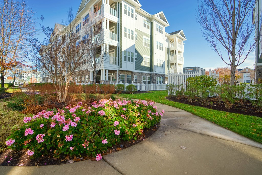 a sidewalk with flowers in front of an apartment building