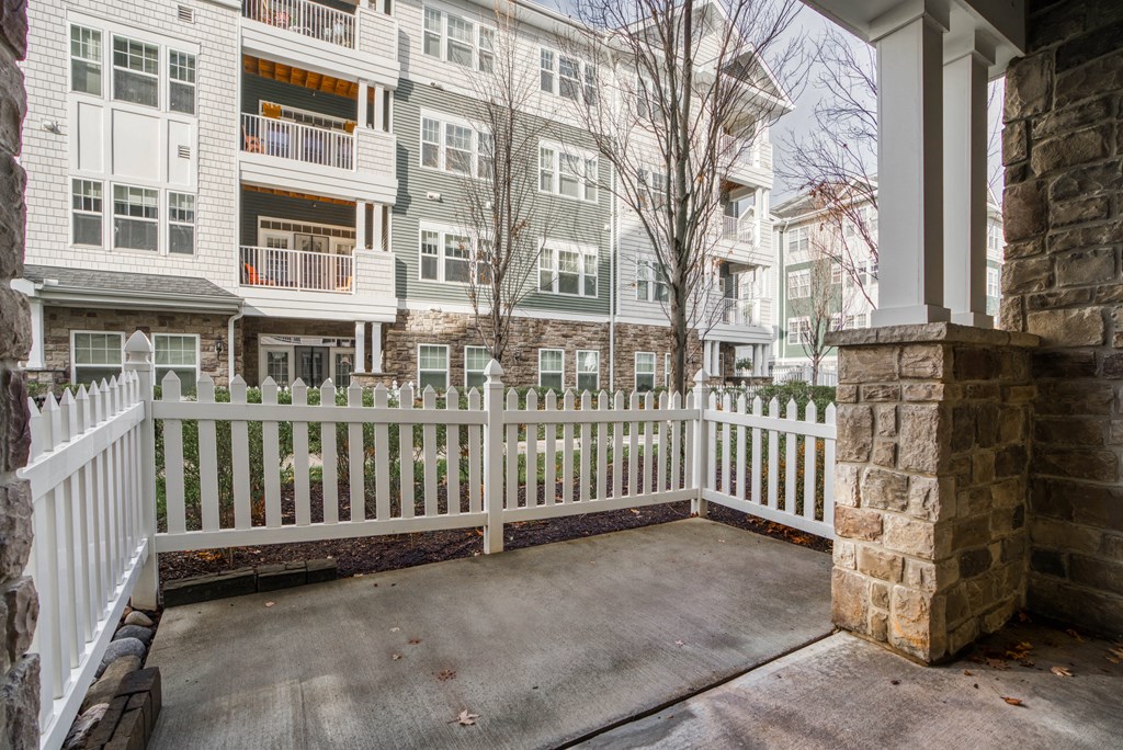 the front porch of an apartment building with a white fence
