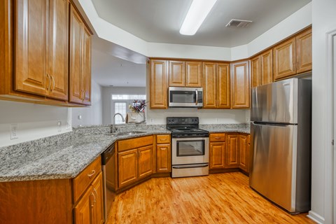 a kitchen with wooden cabinets and granite counter tops and stainless steel appliances