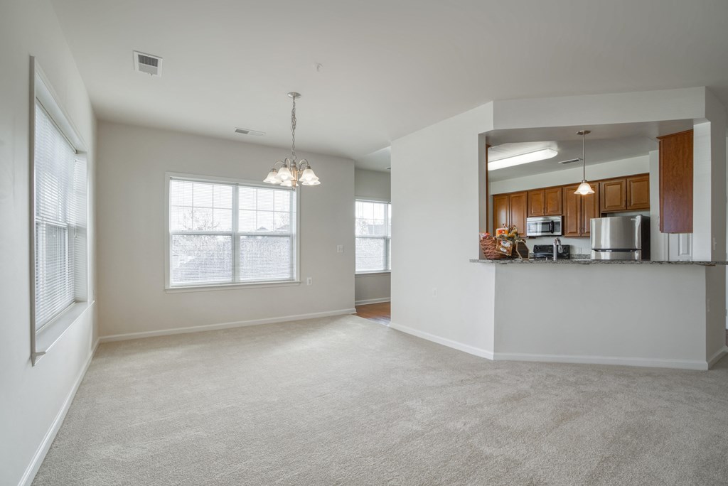 an empty living room with a kitchen in the corner