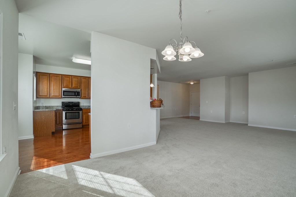 an empty living room and kitchen with wood flooring and white walls