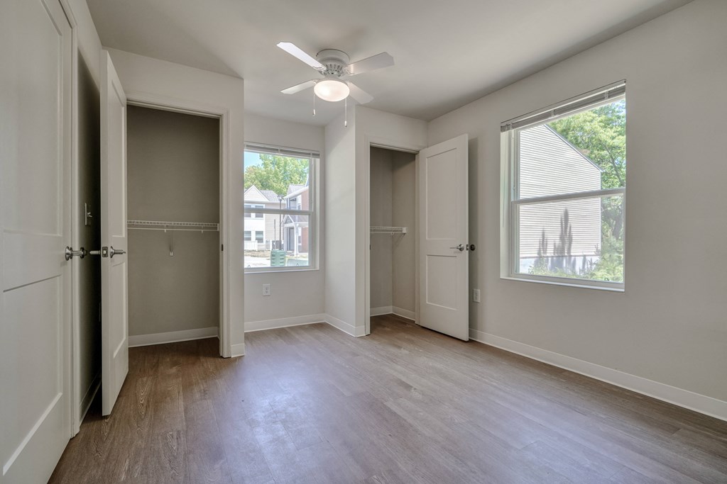 an empty living room with wood floors and a ceiling fan