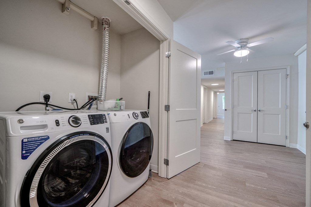a laundry room with a washer and dryer and a hallway with a door