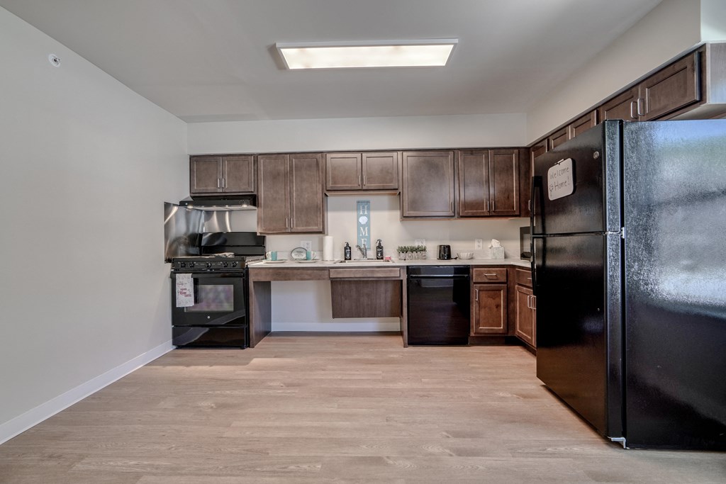 an empty kitchen with black appliances and wooden cabinets