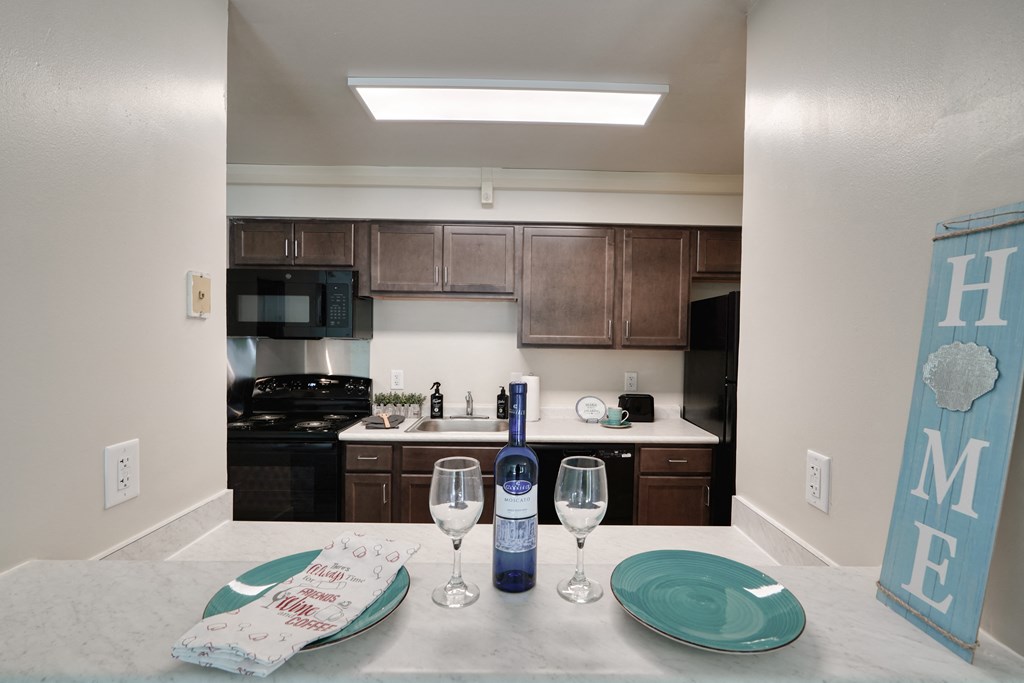 a kitchen with a island and a table with wine glasses