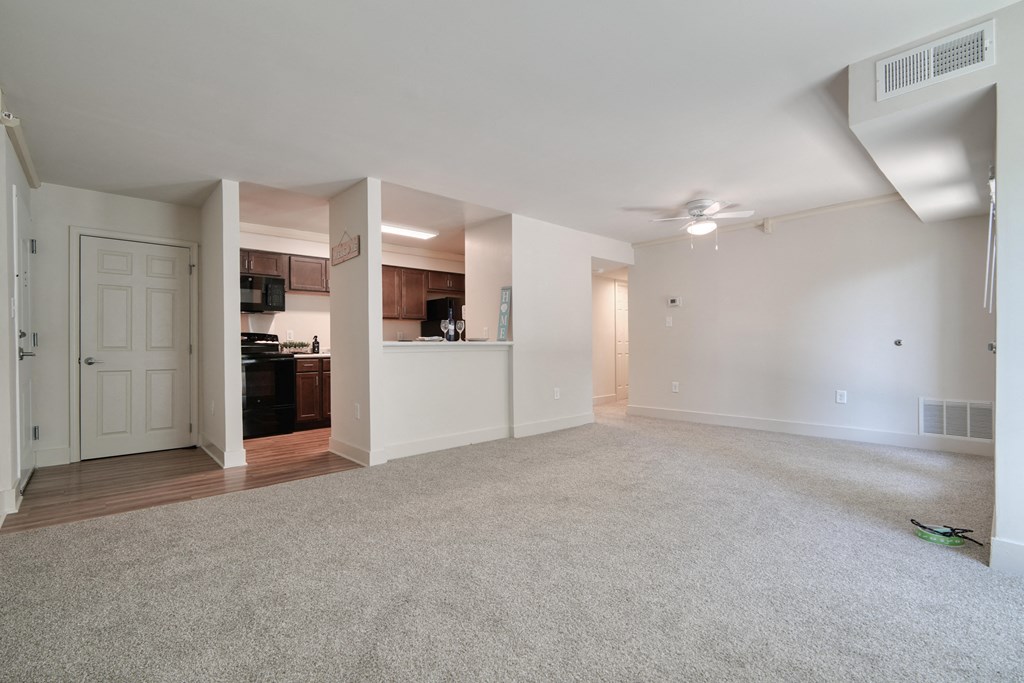 an empty living room with white walls and a ceiling fan