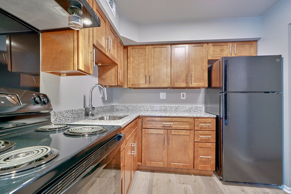Kitchen of one bedroom with wooden cabinets and stainless steel appliances