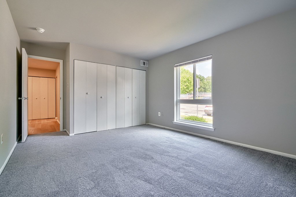 One bedroom with carpet a large window and a large closet