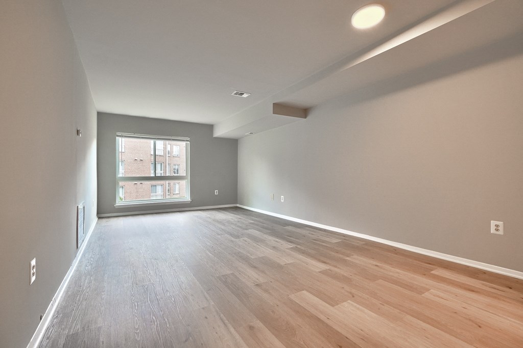 an empty living room with wood flooring and a window