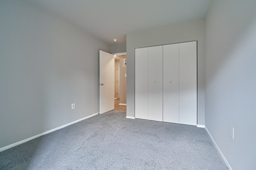 a bedroom with a closet and a carpeted floor