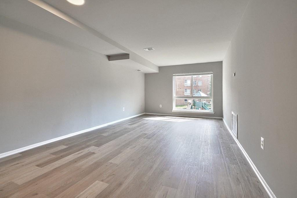 an empty living room with wood floors and a window