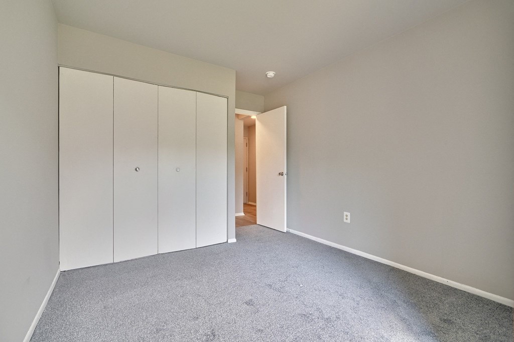a bedroom with white cabinets and carpet and a door to a hallway