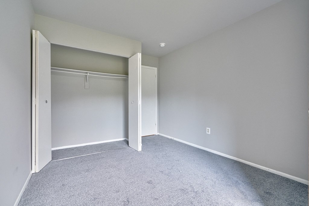 an empty bedroom with white walls and a closet