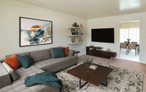 A living room with a grey couch, a coffee table, and a painting on the wall.