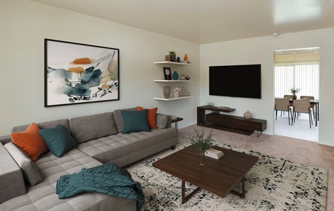 A living room with a grey couch, a coffee table, and a painting on the wall.