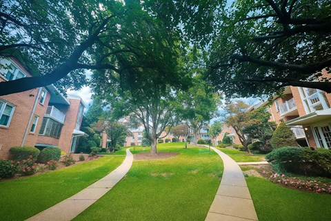 A tree-lined walkway leads through a residential neighborhood.