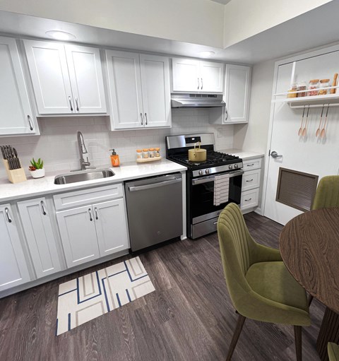 A kitchen with white cabinets and a green chair.