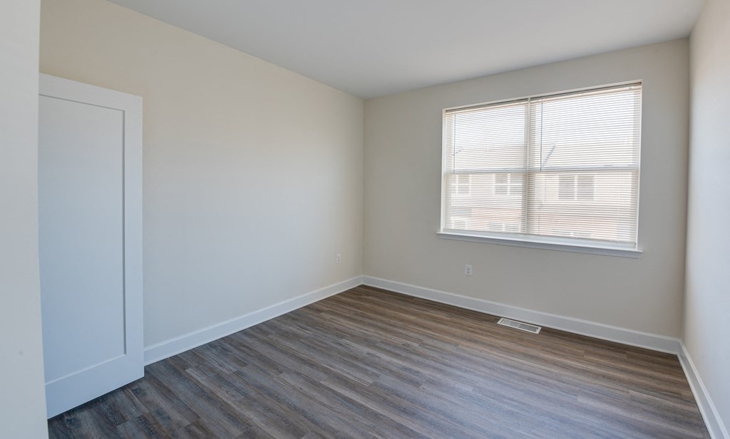 an empty room with wood flooring and a window