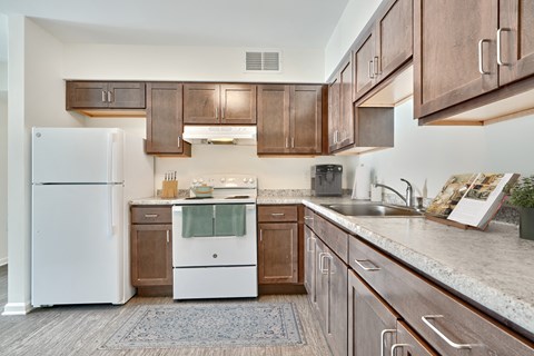 A kitchen with a white refrigerator and wooden cabinets.