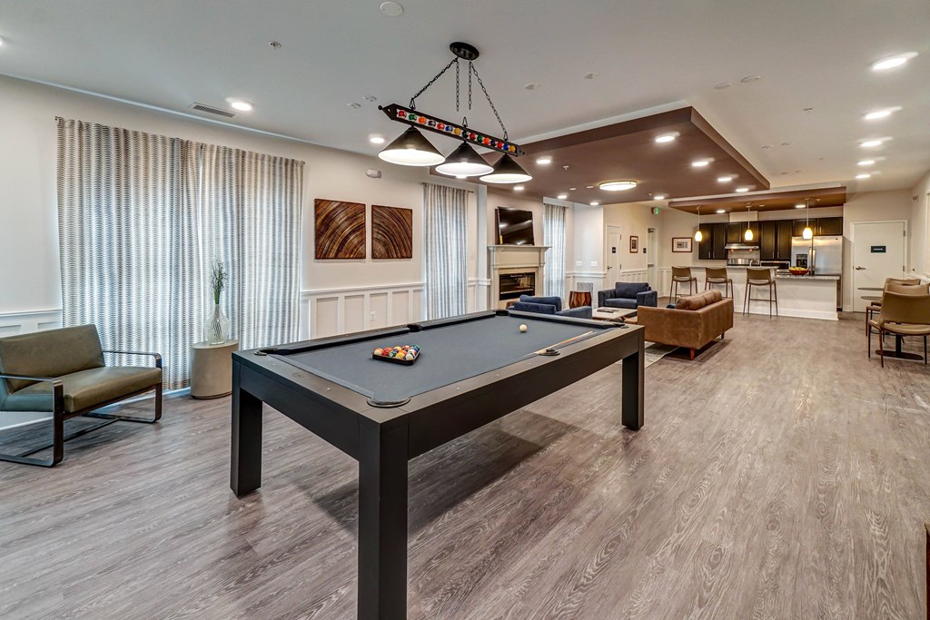 A billiard table is in the middle of a room with a pool table light hanging from the ceiling.