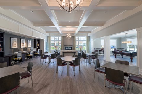 A large room with tables and chairs and a pool table.