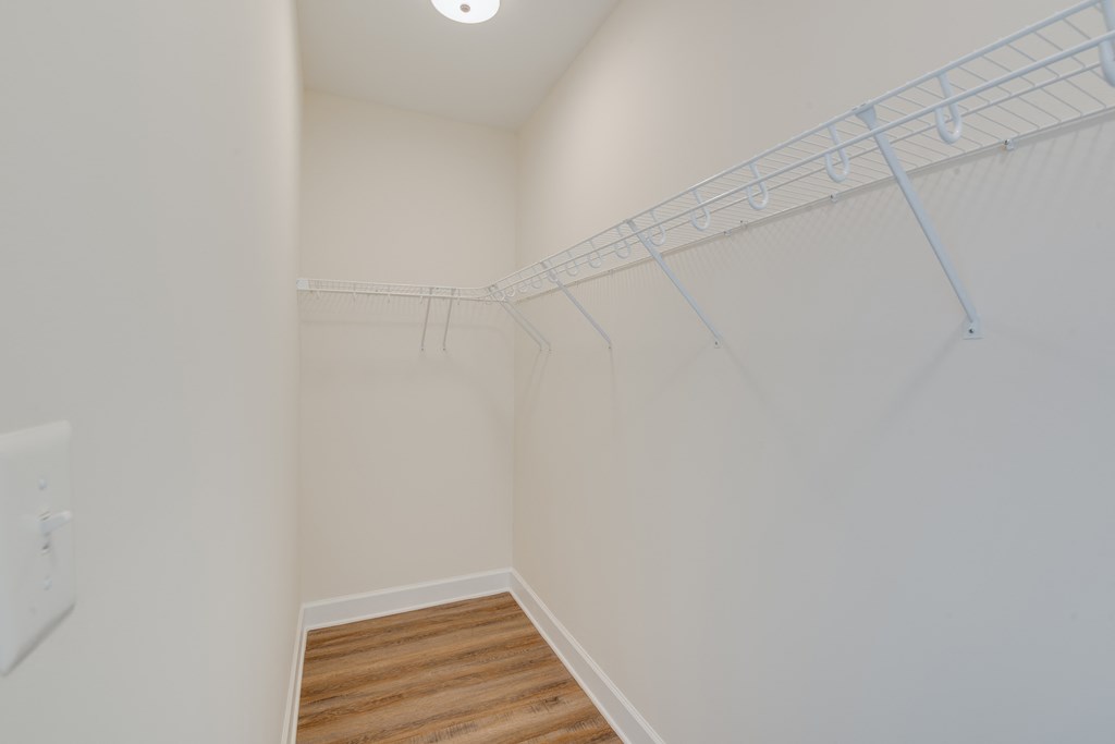 an empty closet with white walls and wood flooring