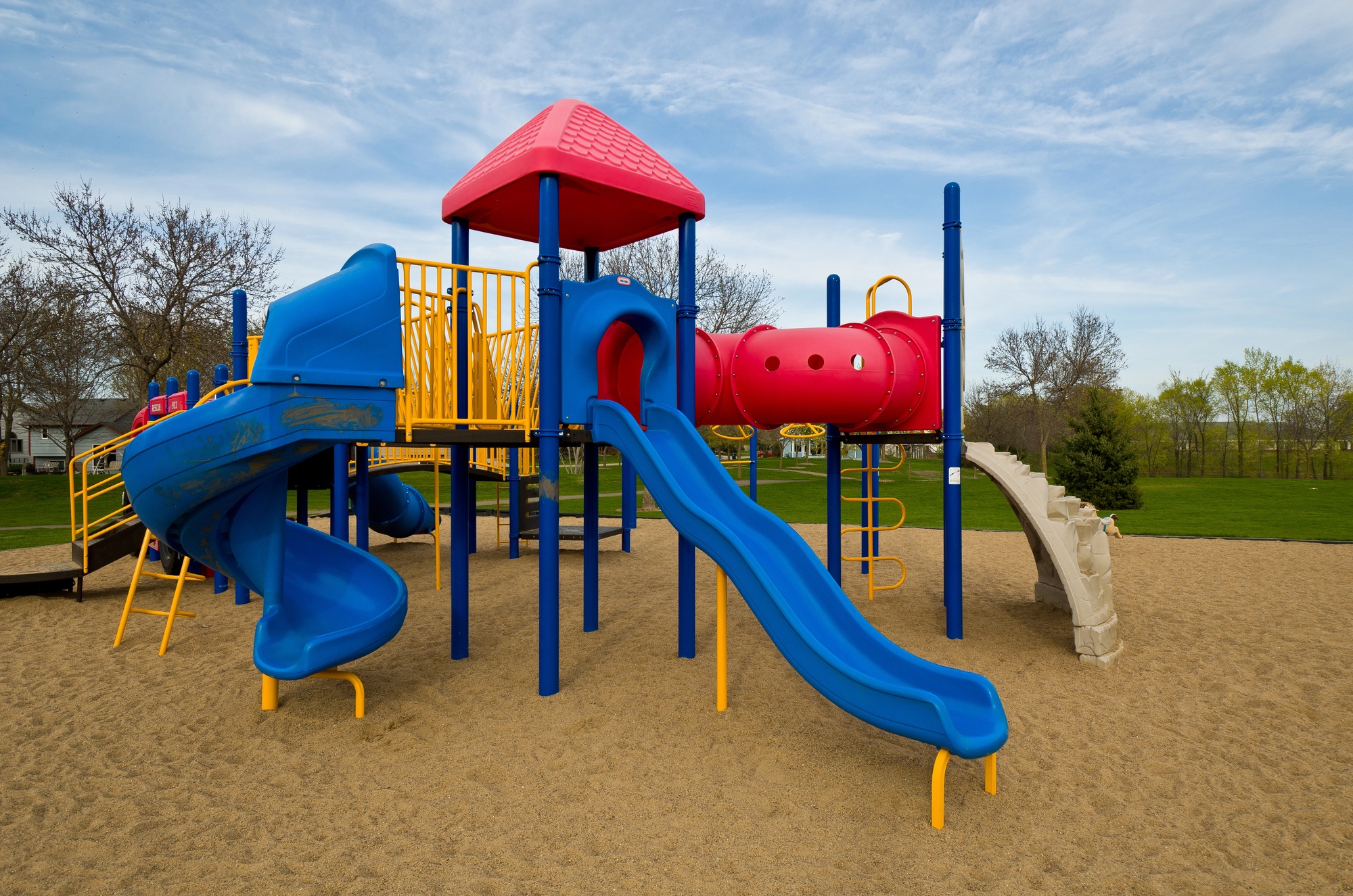 A playground with a blue and red slide and a red roof.