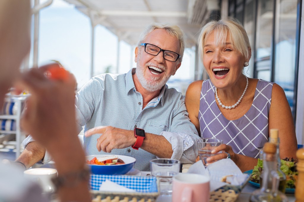 an older man and woman sitting at a table eating food