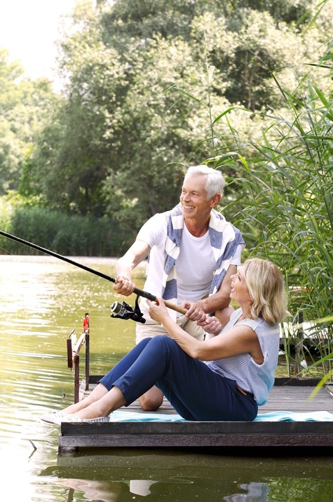 A man and a woman are fishing on a dock.
