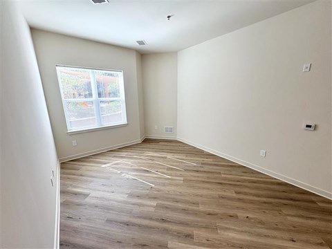 A room with wooden flooring and a window overlooking a building.