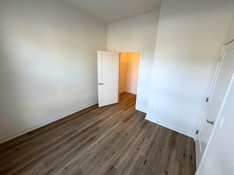 A room with a white door and wooden flooring.