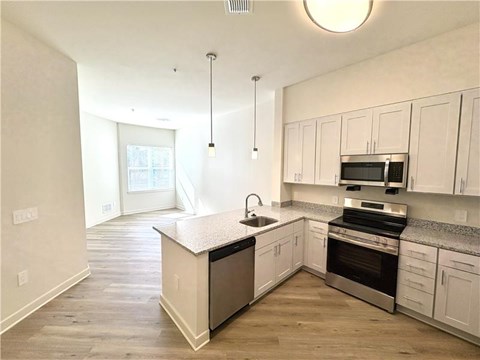 A kitchen with white cabinets and a black countertop.