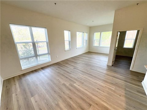 A room with wooden flooring and large windows.
