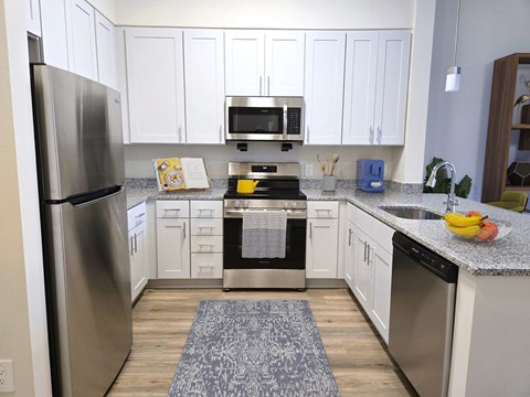 A kitchen with white cabinets and a stainless steel refrigerator.