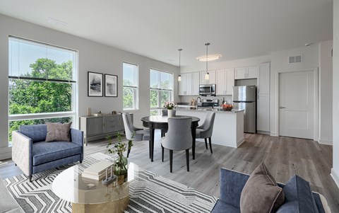 A modern kitchen and dining area with a view of trees outside the window.