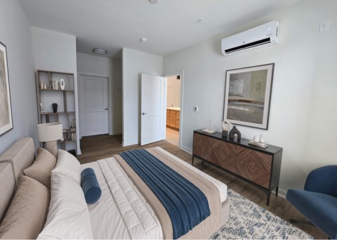 A bedroom with a bed, a couch, a chair, and a painting on the wall.